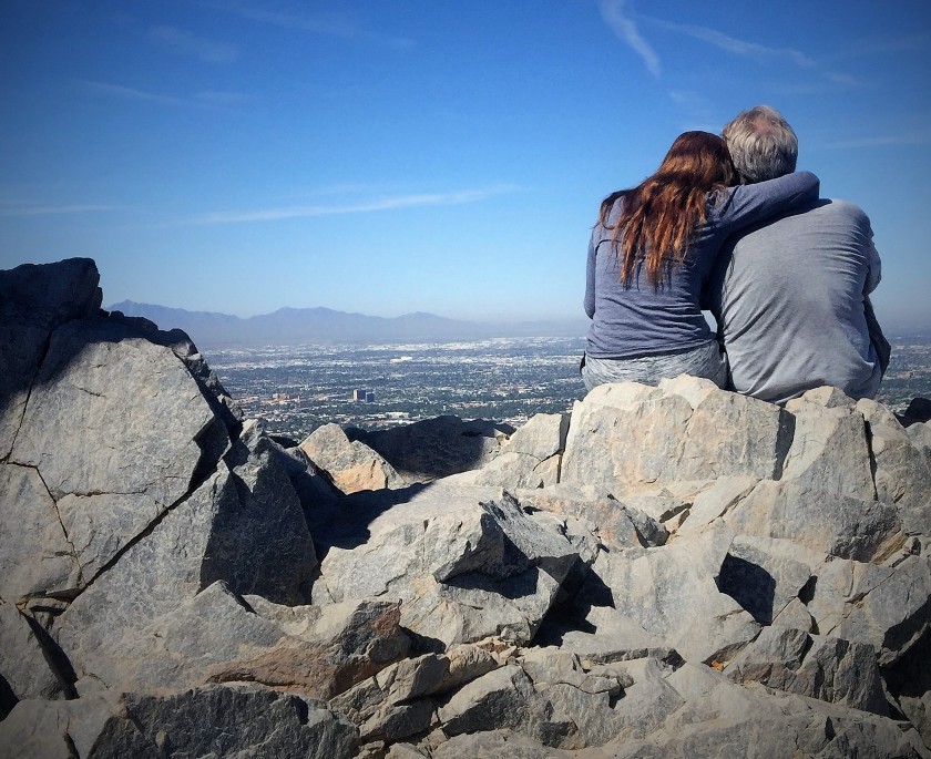 a couple cuddling on top of mountain peak looking out. Piestewa Peak hiking trail on Phoenix Mountains in Phoenix , Arizona
